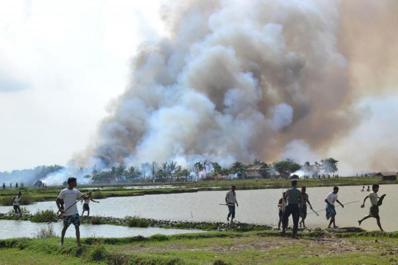 Haziran 2012'de yaşanan şiddet olayları sırasında silah taşıyan yerel Budistler yanan bir köyden uzaklaşıyor.  Fotoğraf İnsan Hakları İzleme Örgütü.jpeg