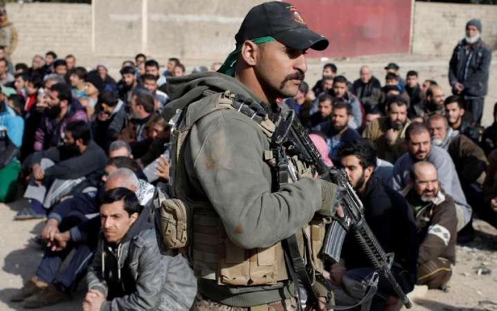 Musul kurtarıldıktan sonra gözaltındakiler arasında IŞİD militanı bulmak için kimlik kontrolü yapan Iraklı askeri-Kasım 2017.jpg