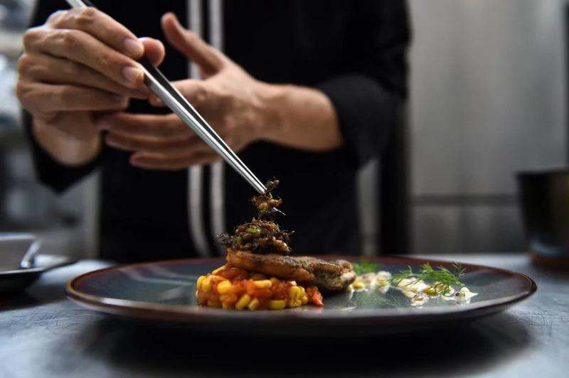 Yenilebilir kanatlı karıncalar, Bangkok'taki üst düzey böcek tabanlı bir bistro olan Insects in the Backyard'da bir balık filetosunun üzerine yerleştirilir (AFP).jpg