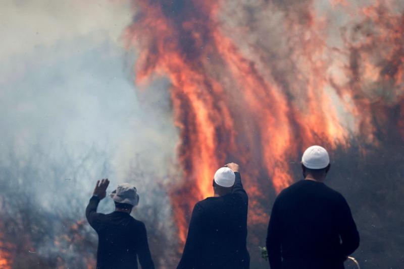 Güney Lübnan'dan atılan roketlerin Golan Tepeleri'nin Banyas bölgesine isabet etmesinin ardından bir tarlada alevler yükselirken, yangını izleyen bölge sakinlerinden Dürzi erkekler, 9 Haziran 2024 AFP.jpg