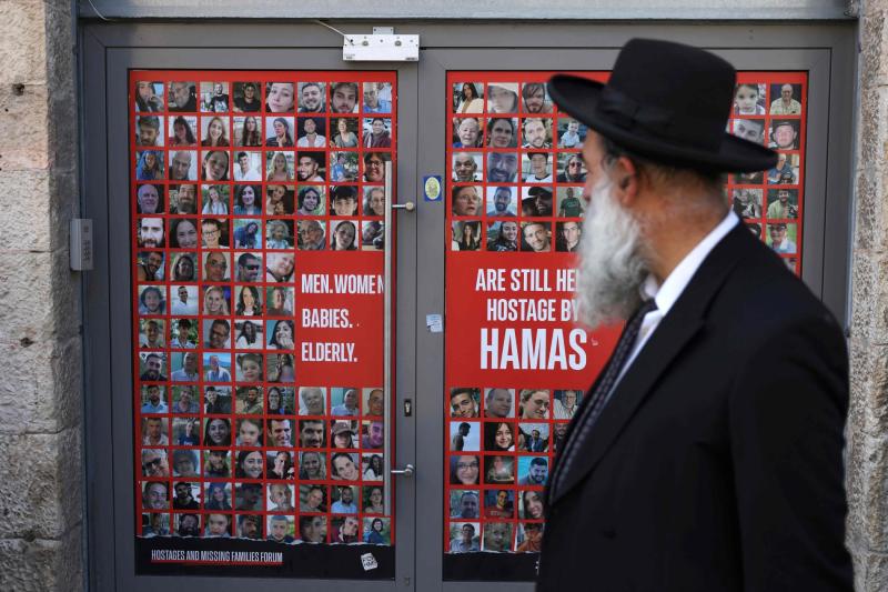 Gazze'deki İsrailli rehinelerin posterlerinin asılı olduğu Kudüs'teki bir mağazanın önünden geçen bir İsrailli, 13 Ekim 2024 / Fotoğraf: AFP