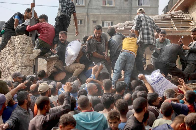 Gazze Şeridi'nin orta kesimlerindeki Deyr el-Belah'ta bulunan Birleşmiş Milletler Yakın Doğu'daki Filistinli Mültecilere Yardım ve Bayındırlık Ajansı (UNRWA) yardım dağıtım merkezinde dağıtılan un çuvallarını alabilmek için mücadele eden Filistinliler, 3 