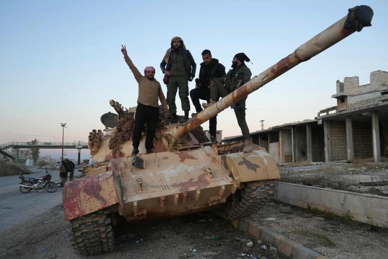 Suriye ordusundan ele geçirdikleri bir tankın üzerine çıkan HTŞ ve ona bağlı grupların üyeleri, 30 Kasım 2024 / Fotoğraf: AFP