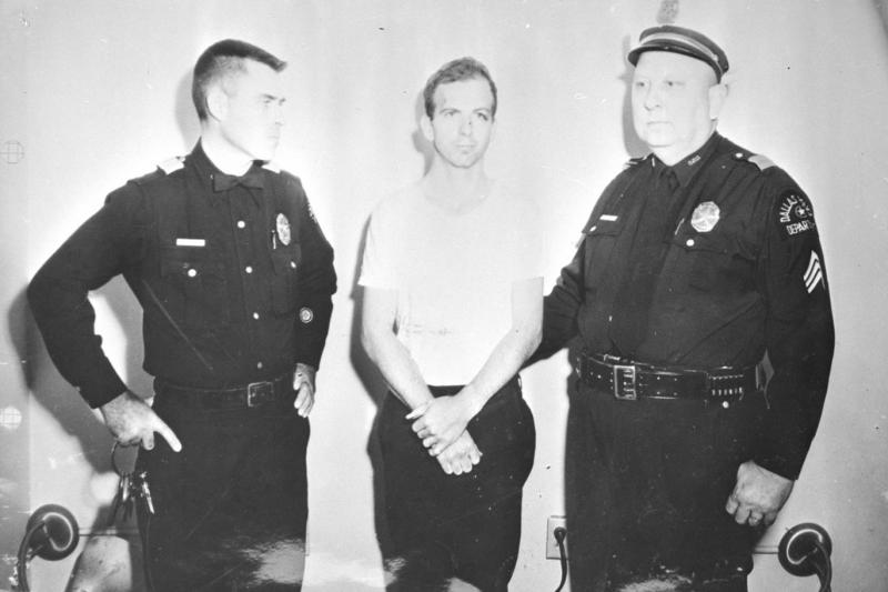 Lee Harvey Oswald ve iki polisin Oswald'ın tutuklanmasından sonra çekilmiş fotoğrafı (National Archives)