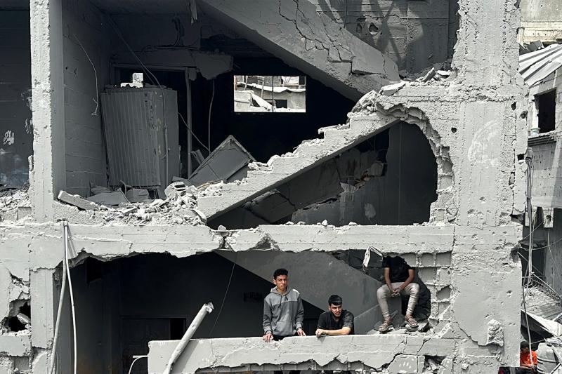 İsrail'in Gazze'deki Şucaiyye Mallesi’nde bir eve düzenlediği saldırının ardından yıkılan evlerin arasında kalan Filistinliler, 9 Nisan 2025 / Fotoğraf: Reuters