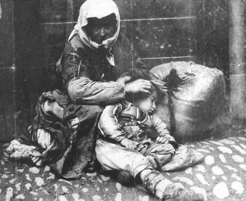 Ermeni anne ile çocuğu, bir bohçayla kaldırım kenarında oturuyorlar, 1918.jpg